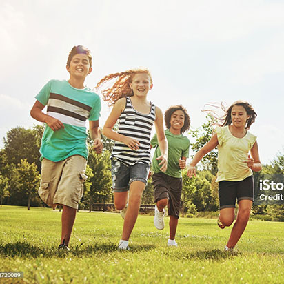 Vier Kinder rennen über eine Wiese.